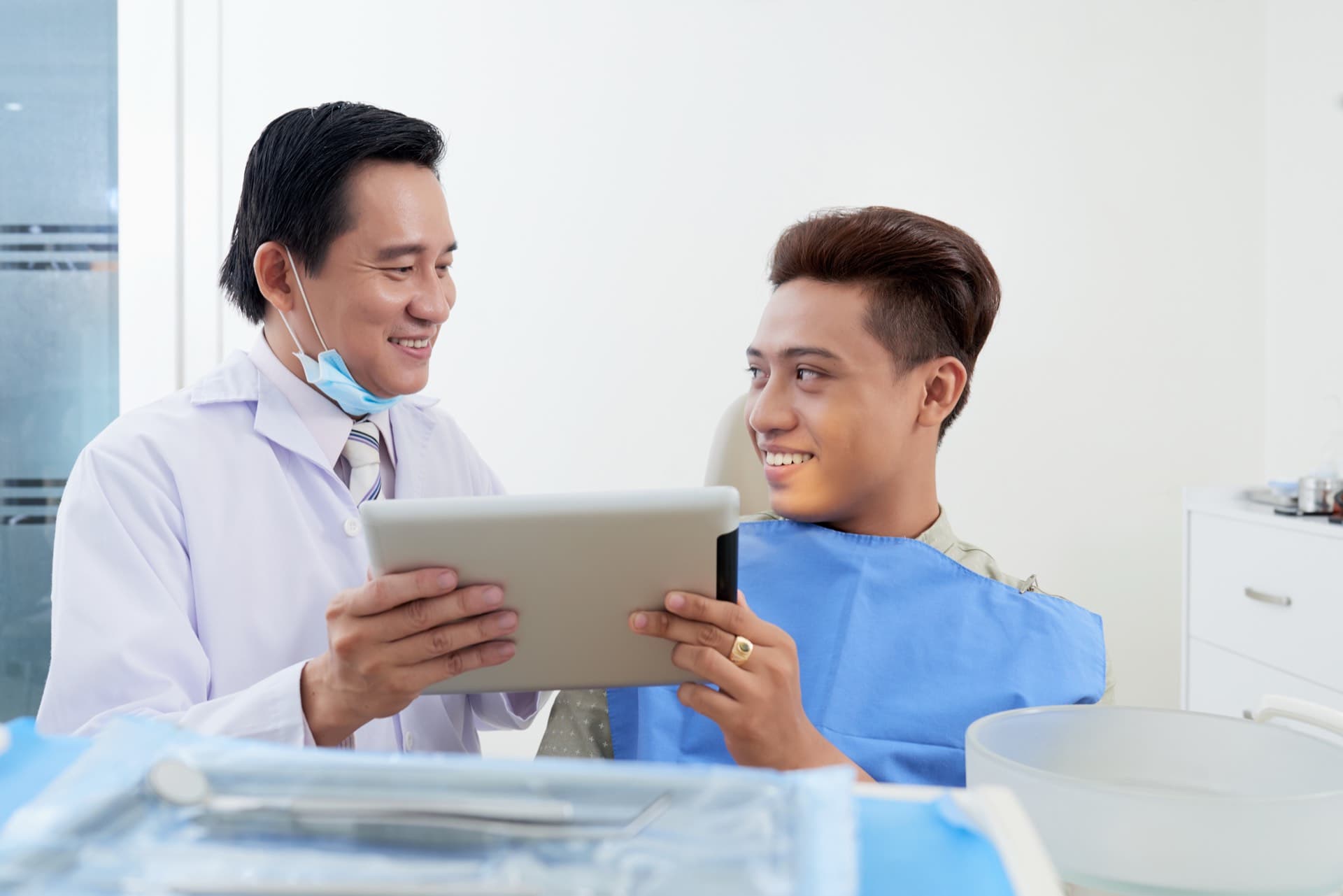 Asian dentist consulting a patient with a tablet