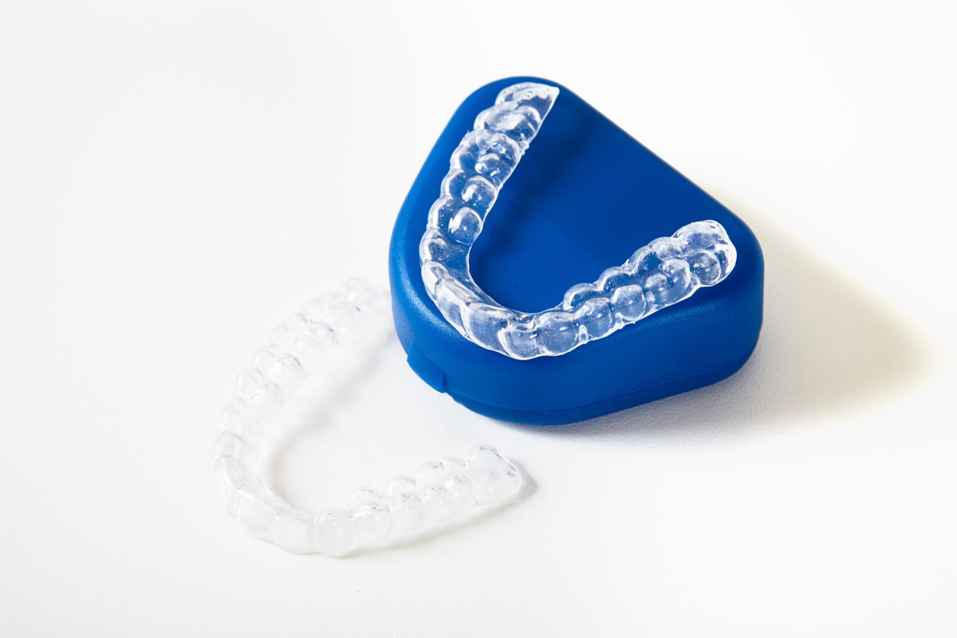 Two clear retainer trays resting on and beside a blue storage case